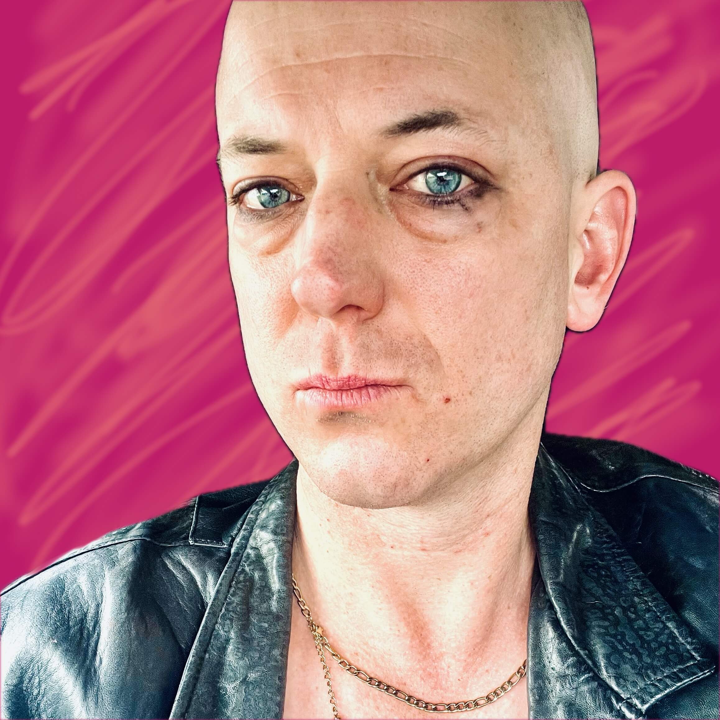 A posey gothic looking non-binary person with a shaved head.